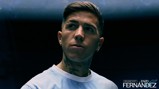 Individual in a light blue shirt with tattoos on neck and a serious expression, dark background with text: 'Welcome to City Enzo Fernández'.