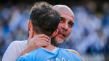 Two Manchester City players embracing on the field, one wearing a blue jersey with 'City' printed on it.