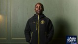 A person in a Manchester City hoodie. The backdrop features 'Asia Tour 26' presented by Experience Abu Dhabi in the corner.