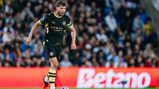 A Manchester City player in black kit with Etihad Airways branding dribbles the ball on the field during a match.