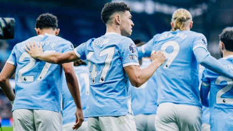 Manchester City players celebrating on the field. The image shows players wearing Manchester City jerseys with visible names and numbers. Notably, numbers 9 (Haaland) and 47 (Foden) can be seen.