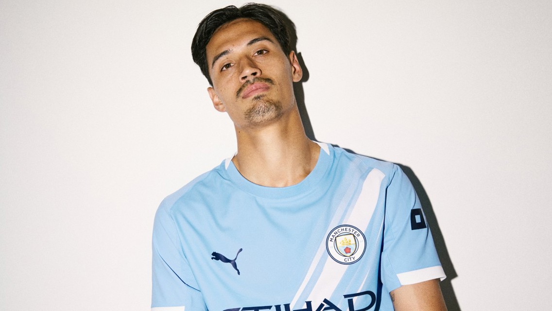 Person in a Manchester City jersey with Puma logo, blurred face.