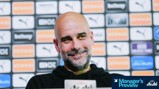 Blurred face of a person speaking at a press conference with a background featuring sponsorship logos including Puma and Etihad.
