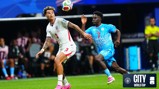 Two soccer players, one in a white kit and the other in a blue kit, vying for the ball during a match. The game appears to be part of a World Cup event.