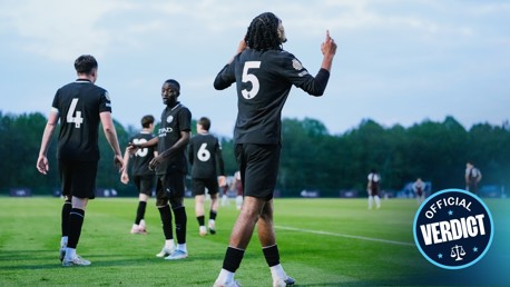A football team wearing black jerseys numbered 4, 5, and 6 celebrate on the field. The player with number 5 gestures upwards. 'Official Verdict' logo in the bottom right corner.