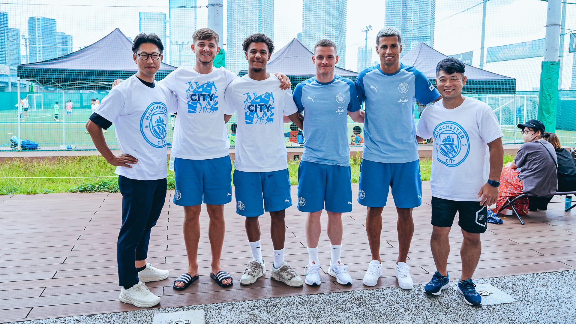 ALL SMILES; James McAtee, Oscar Bobb, Sergio Gomez and Joao Cancelo pose with two of the volunteers.