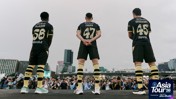 Three people in black Manchester City jerseys standing on a stage facing a large crowd with cameras, part of the Asia Tour '26 event.