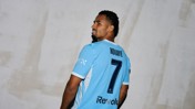 A soccer player wearing a light blue jersey with the name 'NDIAYE' and number 7 on the back looks over his shoulder.