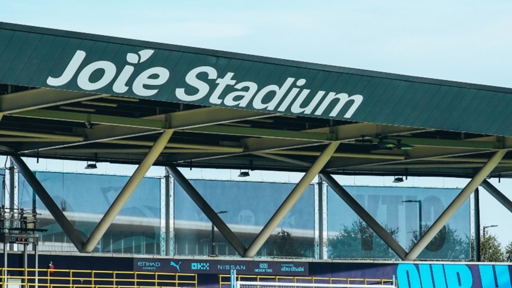 Exterior view of Joie Stadium, showing the stadium roof and goalposts on a clear day.