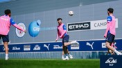 Players in pink training kits, with a ball mid-flight at Manchester City training ground.