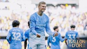 A soccer player in a Manchester City jersey celebrates on the field. Teammates surround him with the 'Ballon D'Or 2026' text overlay.