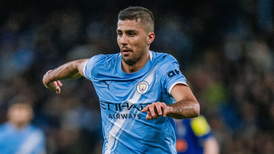 A Manchester City player in action wearing the team's blue kit with 'Etihad Airways' branding.