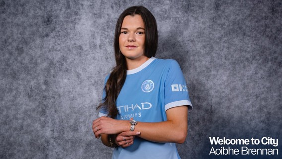 A woman wearing a Manchester City jersey stands against a gray background, with text reading 'Welcome to City Aoibhe Brennan.'