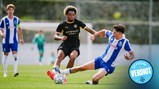 Two soccer players from opposing teams compete for the ball during a match. One player attempts to tackle the other, who is wearing a Manchester City kit.