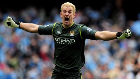 A goalkeeper wearing a Manchester City kit with arms outstretched, on a football field.