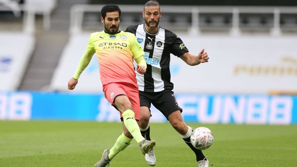 ARAH GAWANG: Ilkay melepas umpan dalam kejaran Andy Carroll