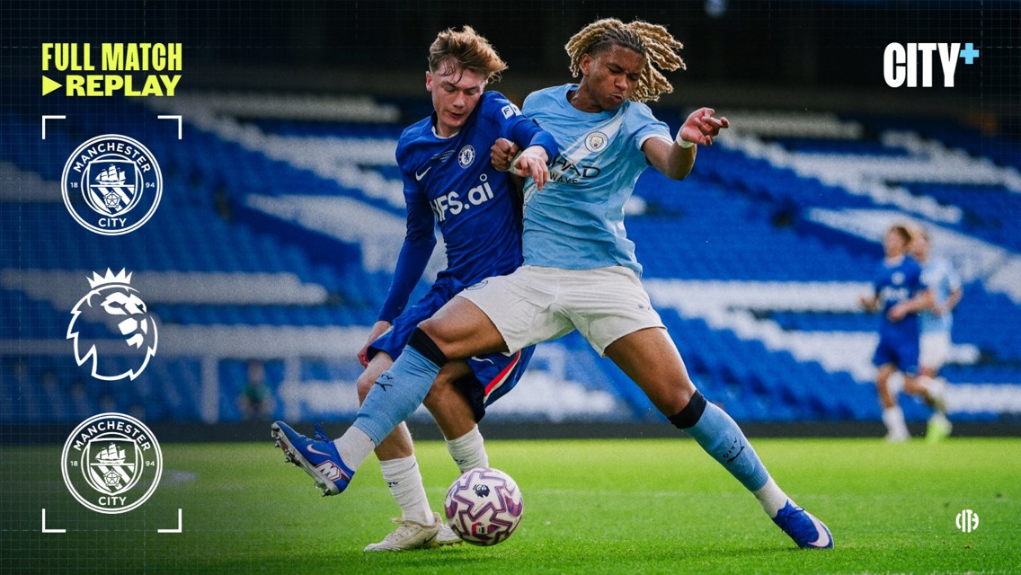 Manchester City player in light blue kit and Chelsea player in dark blue kit compete for the ball on the field during a Premier League match.