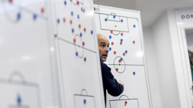 A person strategizing on football tactics with magnetic markers on a whiteboard in a sports setting.