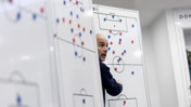 A person strategizing on football tactics with magnetic markers on a whiteboard in a sports setting.