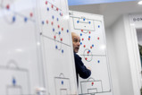 A person strategizing on football tactics with magnetic markers on a whiteboard in a sports setting.