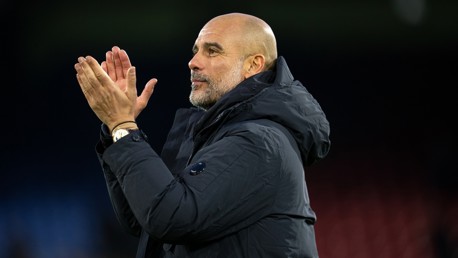 A person wearing a winter jacket, clapping, with their face blurred out.