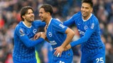 Three Brighton & Hove Albion players celebrating during a football match wearing blue and white striped jerseys.