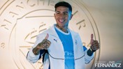Person in a Manchester City jacket giving two thumbs up. Background features Manchester City crest and text 'Welcome to City Enzo Fernandez'.