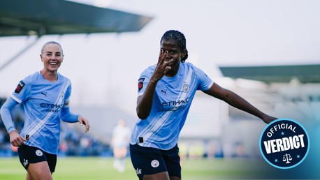 Manchester City Women players celebrating a goal on the field, wearing Manchester City blue kits, with a blurred logo 'Official Verdict' visible.