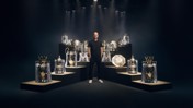 A person standing among various football trophies on platforms with dramatic lighting.