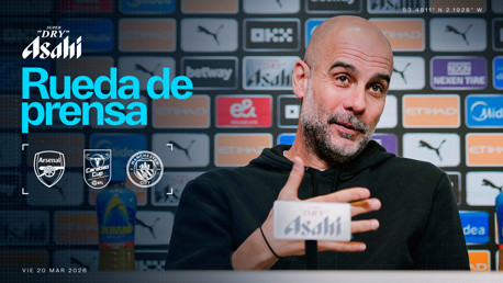 Blurred person at a press conference for Arsenal vs Manchester City in the Carabao Cup on March 20, 2026, with background logos and microphone.