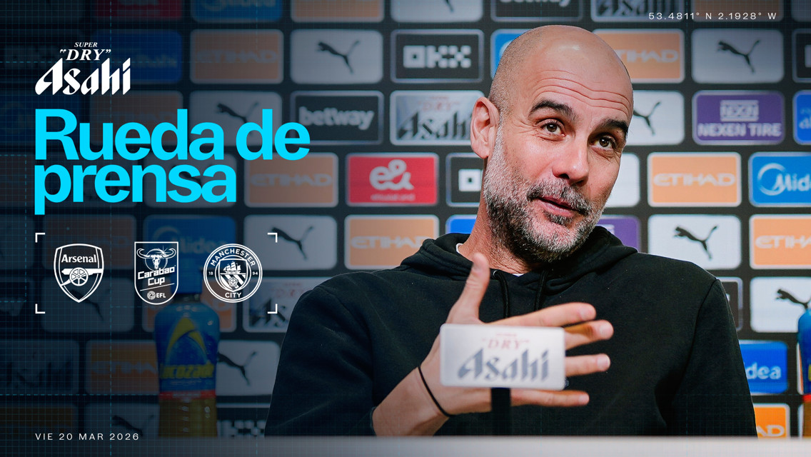 Blurred person at a press conference for Arsenal vs Manchester City in the Carabao Cup on March 20, 2026, with background logos and microphone.