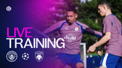 Manchester City players training with the UEFA Champions League logo and team logos in the background.