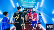 Football players wearing jerseys with team names in Korean are walking up a lit tunnel to enter the field. The image features the logo 'Asia Tour '26' sponsored by Abu Dhabi.