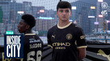 Two men in Manchester City jerseys stand outdoors with a cityscape in the background, marked with 'Inside City.'