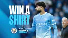 A promotional banner featuring a Manchester City player with the text 'Win a Shirt'. The Manchester City logo and City in the Community Matchday Lottery are also visible.
