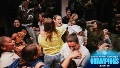 Group celebration of winning the Barclays Women's Super League 2025/26, with people gathered together, some taking pictures and others embracing.