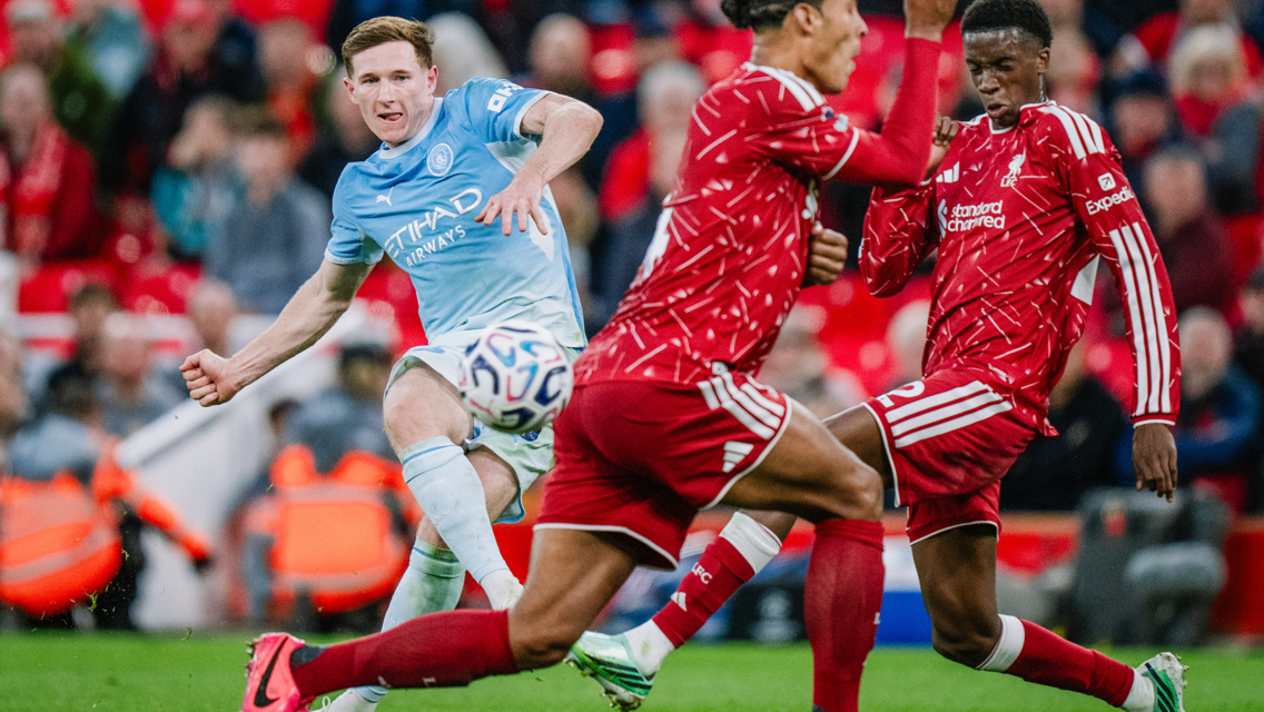 Football players from teams in blue and red kits compete for the ball in a match.
