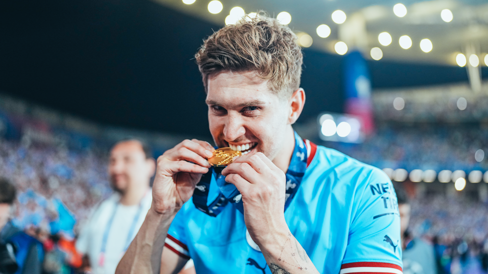 TASTY? : John Stones tries to take a bite of his medal