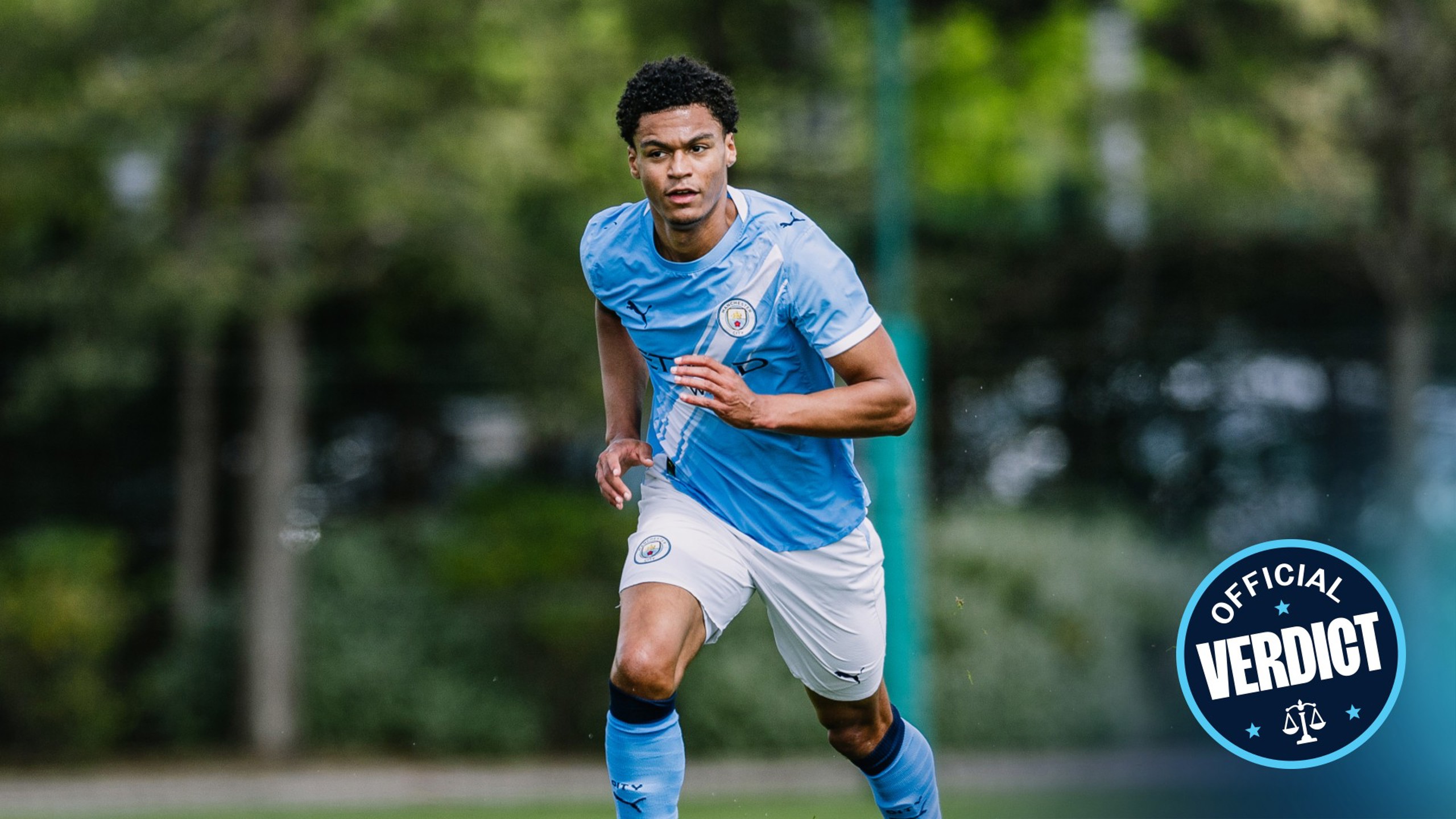 Blurred image of a soccer player in a Manchester City uniform in action on the field, with 'Official Verdict' badge in the corner.