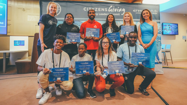 A group of young individuals holding certificates at the Cityzens Giving Young Leaders Summit, with a background banner displaying Cityzens Giving and Etihad Airways.