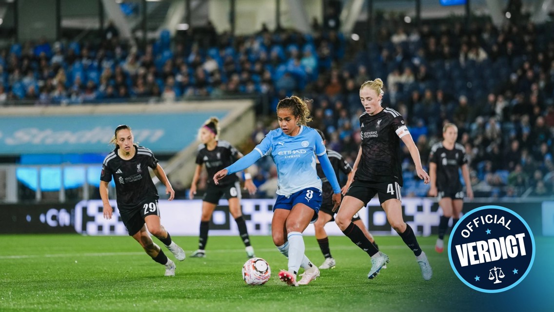 A women's football match between Manchester City and another team wearing dark jerseys, with players in action on the field.