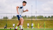 A person in a Manchester City training outfit running on a football field during practice.
