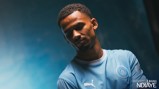 A football player in a light blue Manchester City jersey stands against a gradient background. The text 'Welcome to City' and 'Iliman Ndiaye' appears alongside a Puma logo on the shirt.