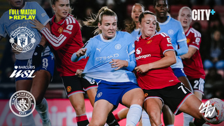 Intense action during a Women's Super League match between Manchester City and Manchester United, featuring players in blue and red kits competing for the ball.