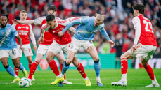 Players from Arsenal and Manchester City in action during a football match, competing for ball possession.