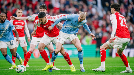 Players from Arsenal and Manchester City in action during a football match, competing for ball possession.