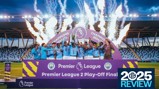 A team in blue uniforms celebrates on stage with a trophy, fireworks in the background. Banner reads 'Premier League 2 Play-Off Final Champions 2024/25'.