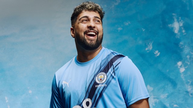 A person wearing a Manchester City Esports Puma jersey with a blurred face against a sky blue background.