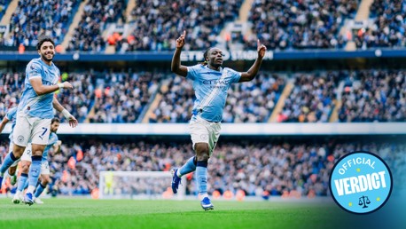 Manchester City players celebrating a goal at Etihad Stadium. A blue badge reading 'Official Verdict' is visible.