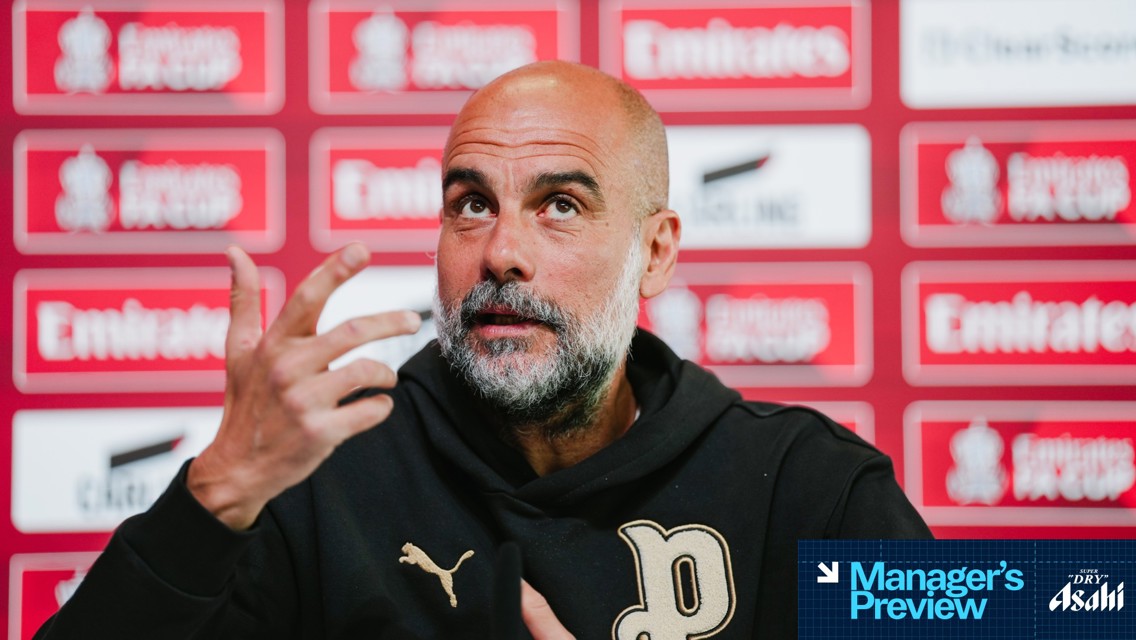A person with a blurred face at a press conference with a red Emirates FA Cup background and a Manager's Preview overlay.